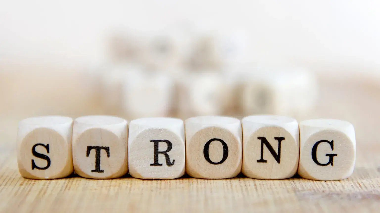 Wooden letter dice spelling the word STRONG on a table.