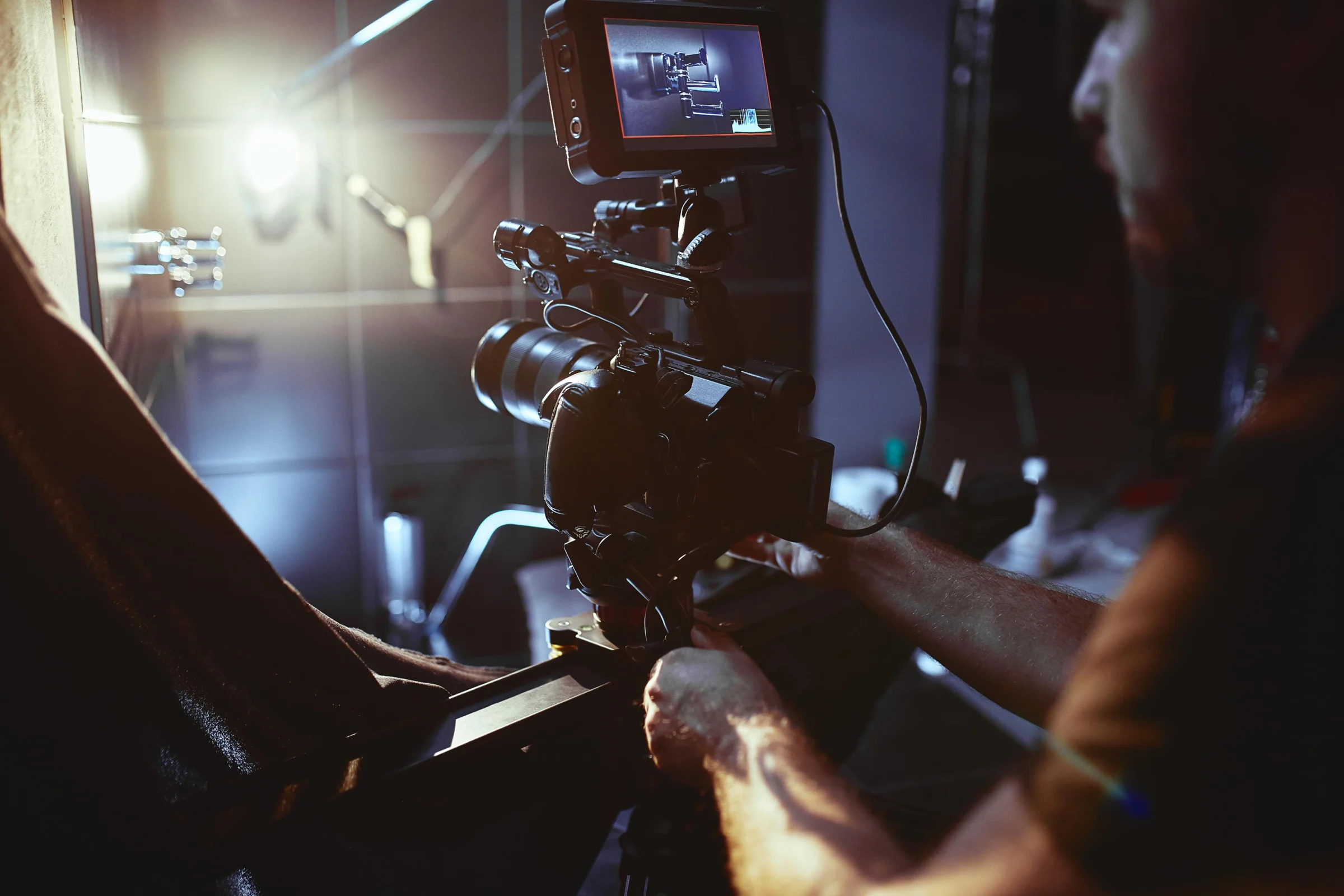 A camera operator adjusting the lens, the monitor displaying the framed shot.