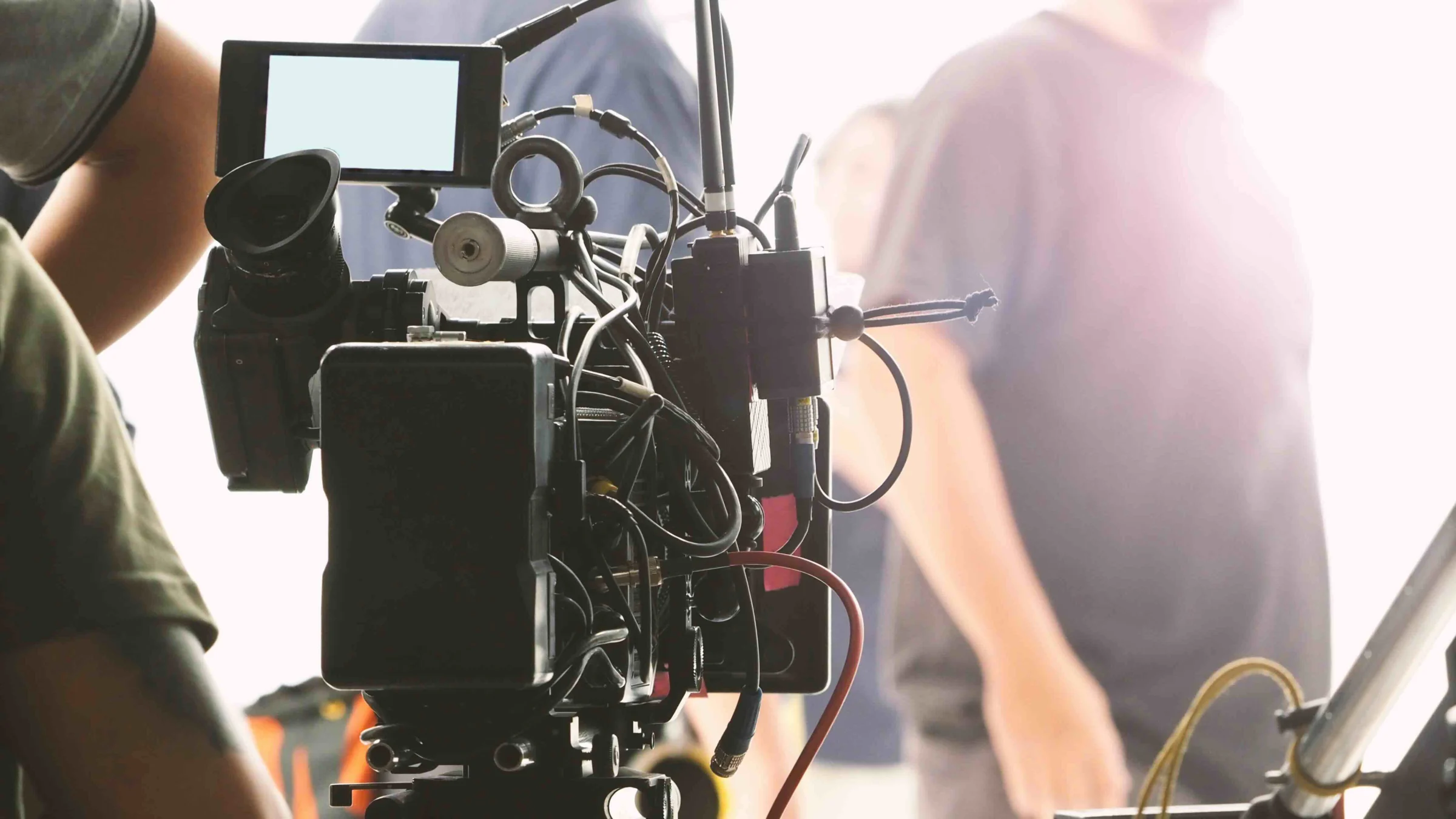 A film camera rig on set, surrounded by crew members during a shoot.