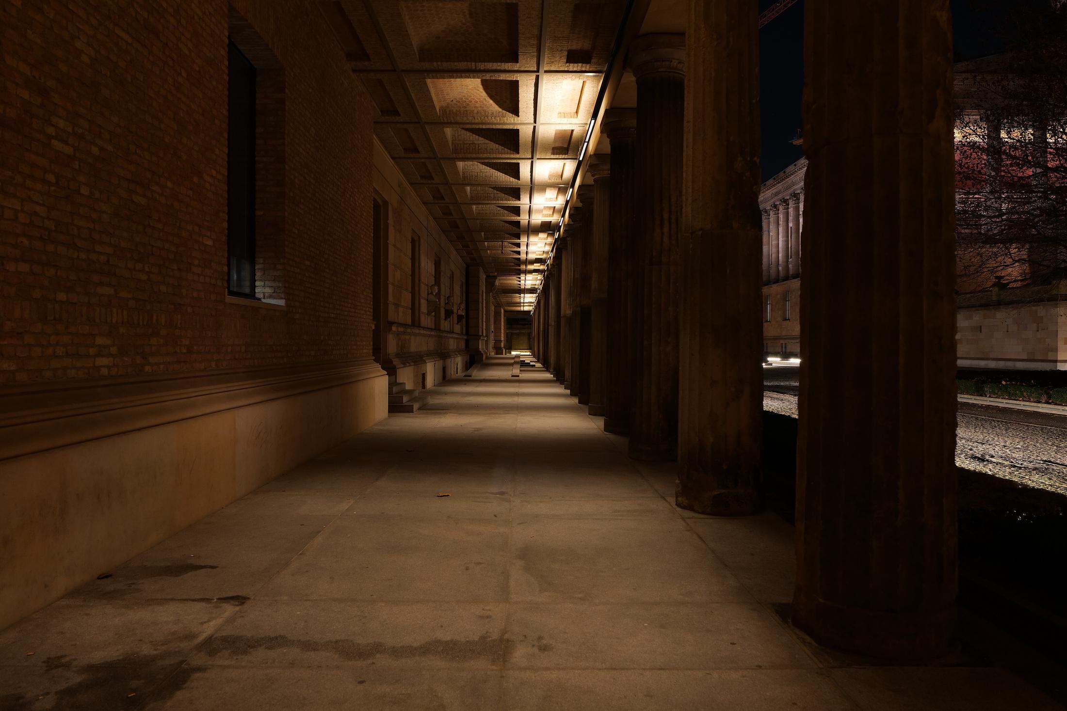 The Museumsinsel colonnade in Berlin at night, its stone columns lit by warm lamps.